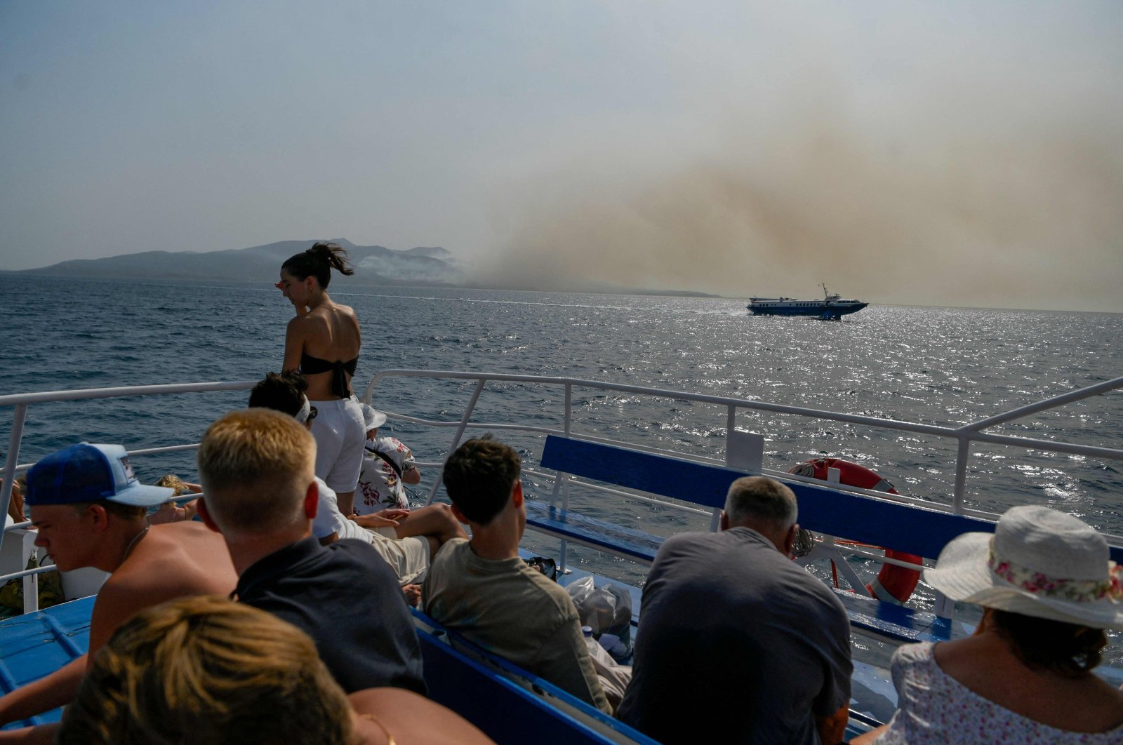 Tourists ride on a ferry to Corfu island as the smoke billows from the fire over the island, Greece, July 25, 2023. (AFP Photo)