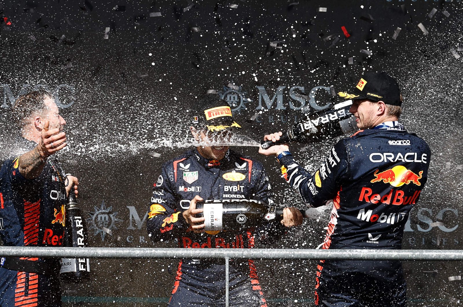 Winner Red Bull Racing&#039;s Dutch driver Max Verstappen (R) and second-placed Red Bull Racing&#039;s Mexican driver Sergio Perez (C) celebrate with a team member on the podium after the Formula One Belgian Grand Prix at the Spa-Francorchamps Circuit, Spa, Belgium, July 30, 2023. (AFP Photo)
