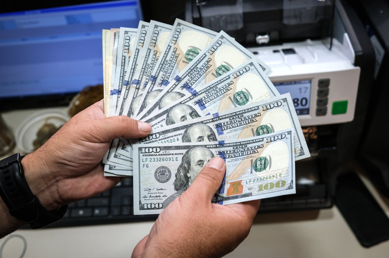 A worker counts U.S. dollars banknotes at an exchange office, Istanbul, Türkiye, Aug. 3, 2023. (EPA Photo)