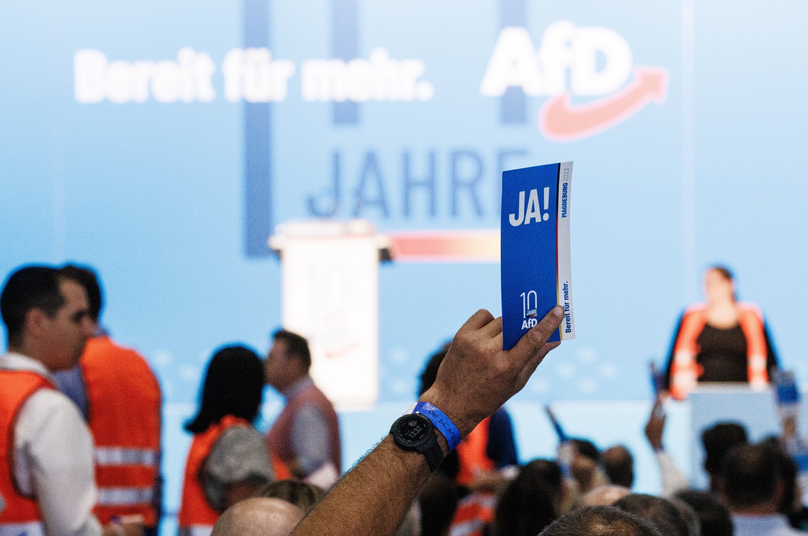 A delegate holds a voting card reading &#039;yes&#039; as members of the counting committee walk in the background (orange vests) during the Alternative for Germany (AfD) party convention in Magdeburg, Germany, 28 July 2023. The Alternative for Germany (AfD) 14th federal party congress takes place in Magdeburg, July 28, 2023. (EPA Photo)